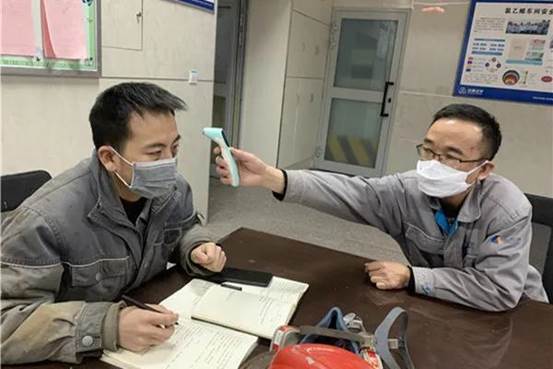 車間值班長王思增給當班班長測體溫（楊歡 攝）